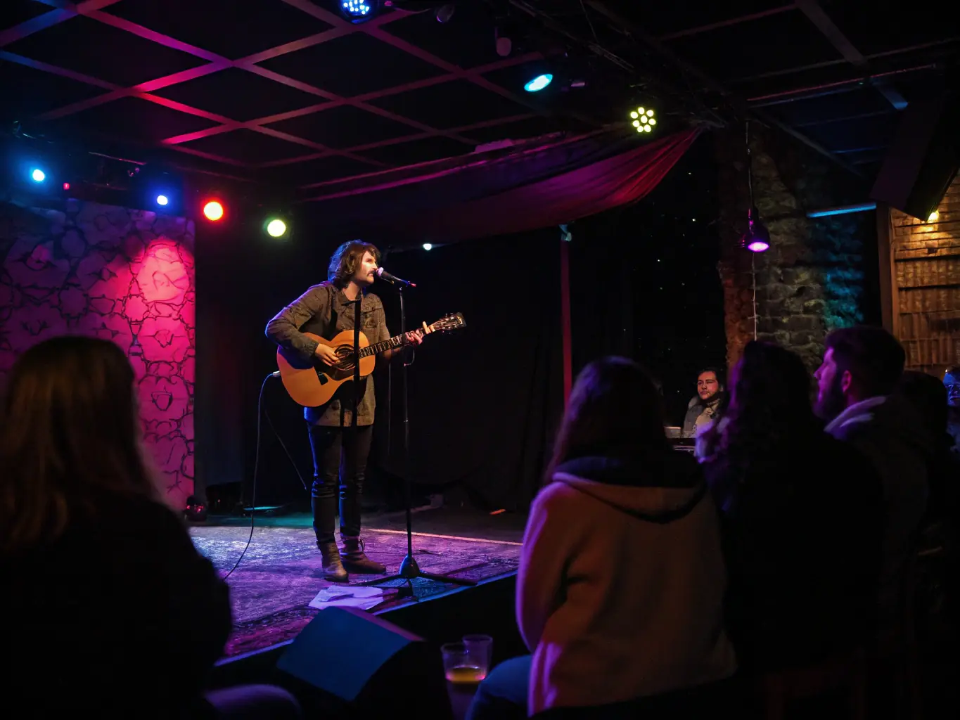 A captivating image of a solo musician playing a guitar on a dimly lit stage, with a focused spotlight highlighting their passionate performance during the TOUT SEUL DEVANT TOUT LE MONDE festival.
