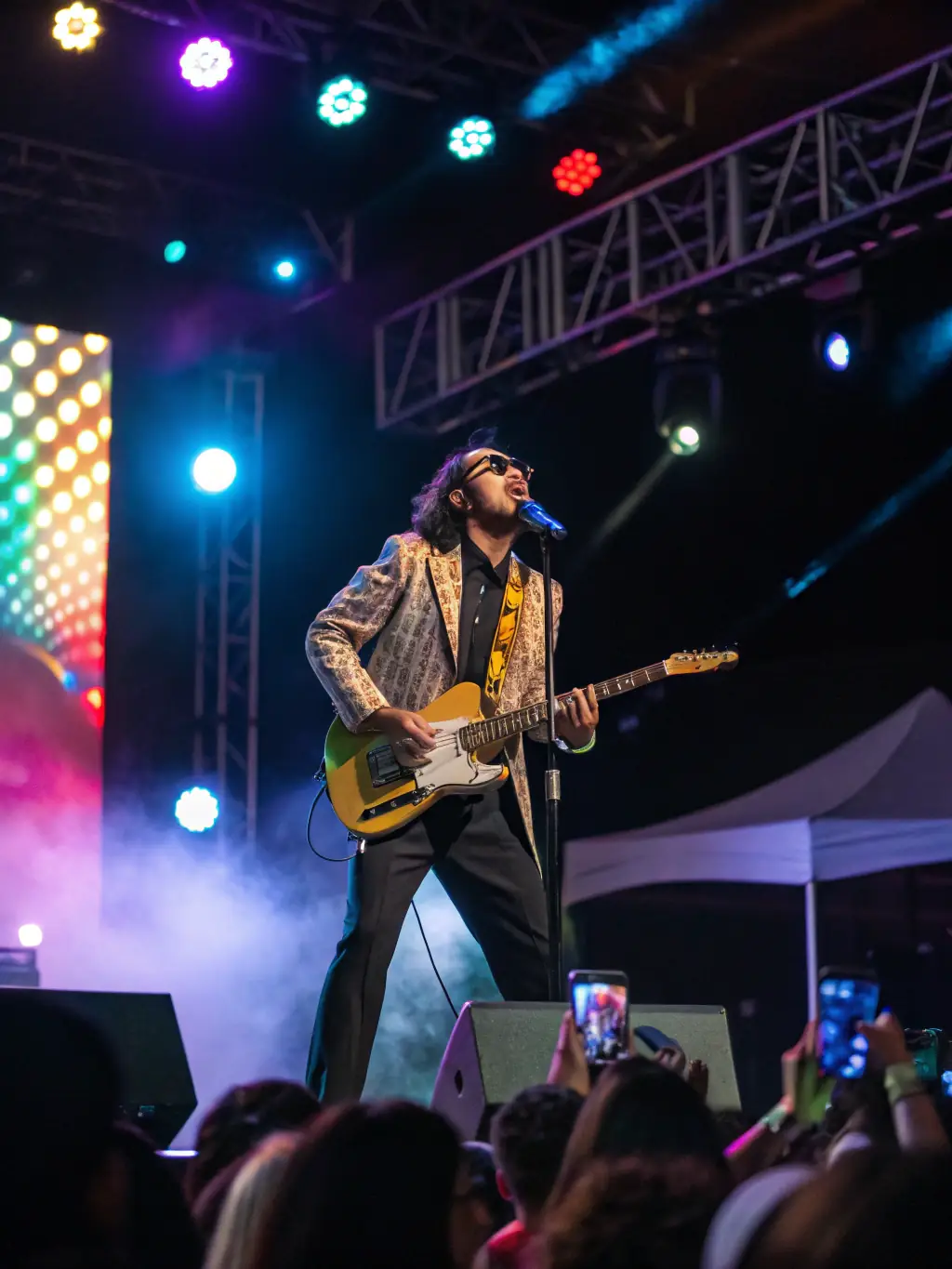 A vibrant photograph capturing a solo musician passionately playing a guitar on stage during the TOUT SEUL DEVANT TOUT LE MONDE festival, bathed in colorful stage lights, showcasing the energy and talent of the performer.